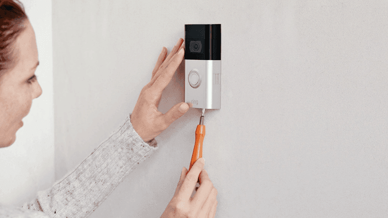 Person screwing in a screw into a ring doorbell