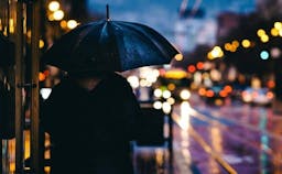 Umbrella held by person while its raining outside