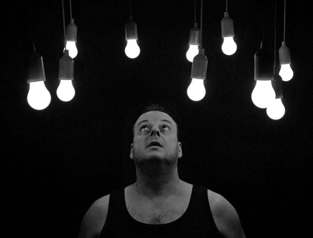 Man staring at light bulbs in black and white picture.