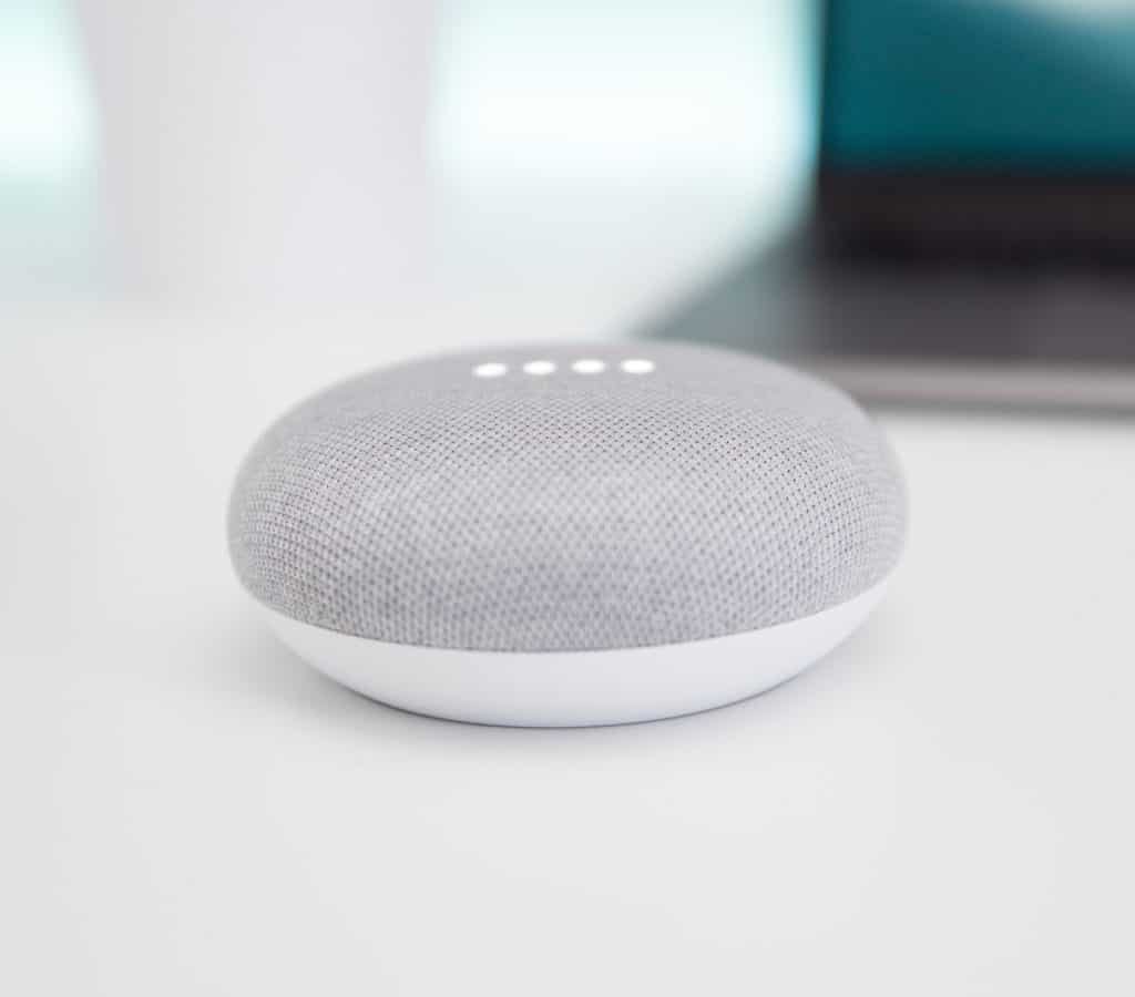 Google Home on white counter with laptop in the back