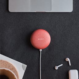 Red google home on desk with laptop