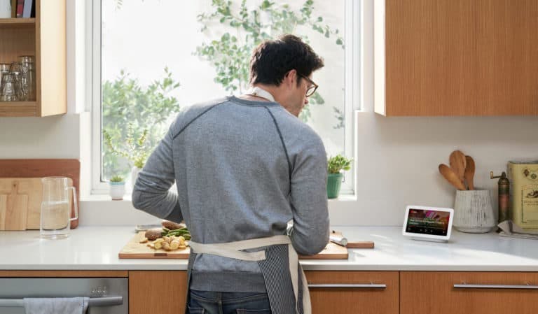 Man cooking in kitchen while looking at tablet for instructions