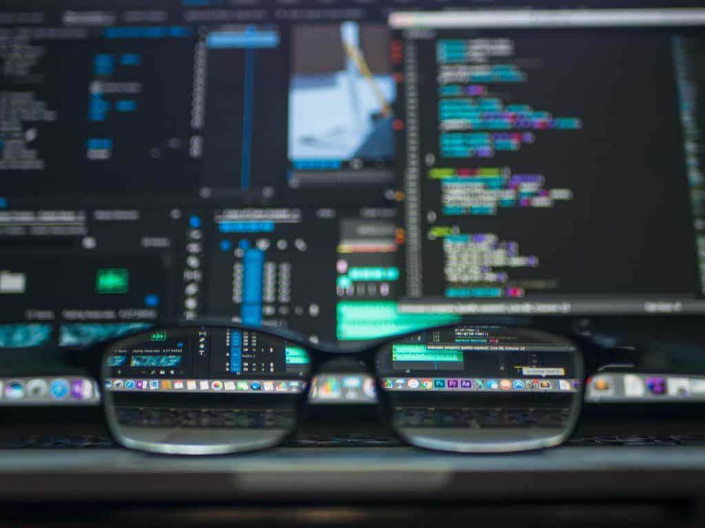Glasses sitting on computer with blurry code screen behind it