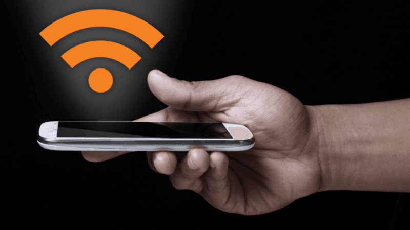 Hand holding smartphone with orange wifi symbol above it