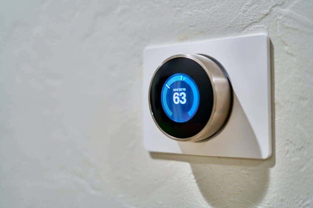Nest thermostat with mounting plate on wall.