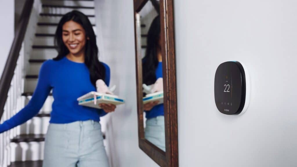 Women smiling inside a home with ecobee thermostat on wall.