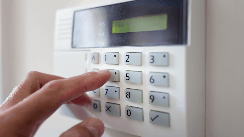 Person pressing a button on their alarm keypad system.