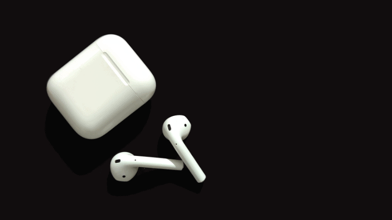 apple airpods with the case on a black table.