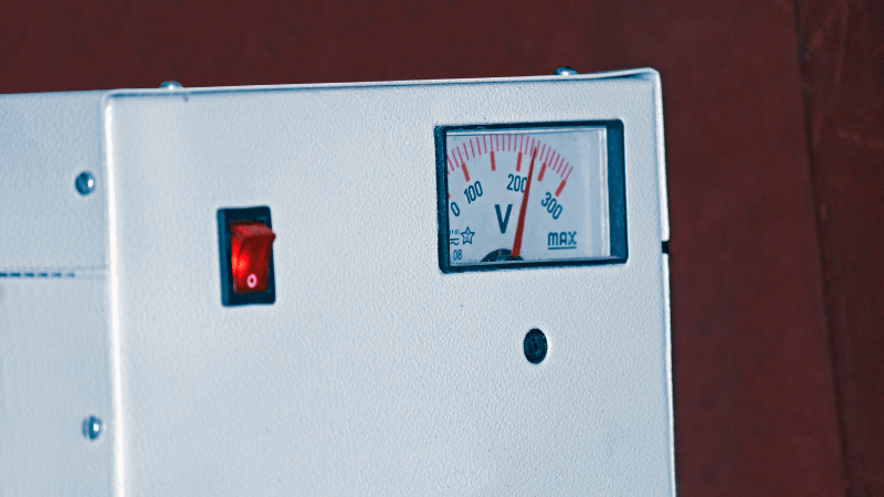 A white voltage meter with a red power switch.
