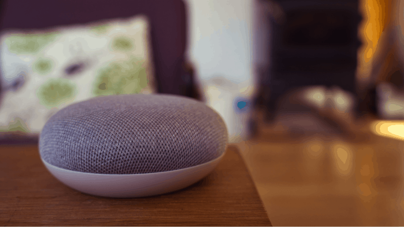 Google home mini speaker on brown end table