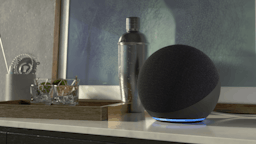 Echo Dot with blue ring light on night stand.