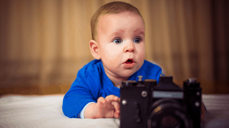 Baby with a camera on bed