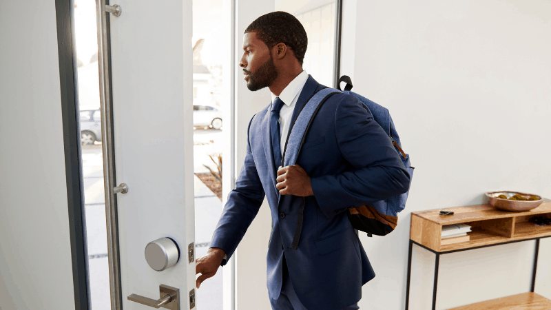 Man leaving home with a navy business suit on and backpack.