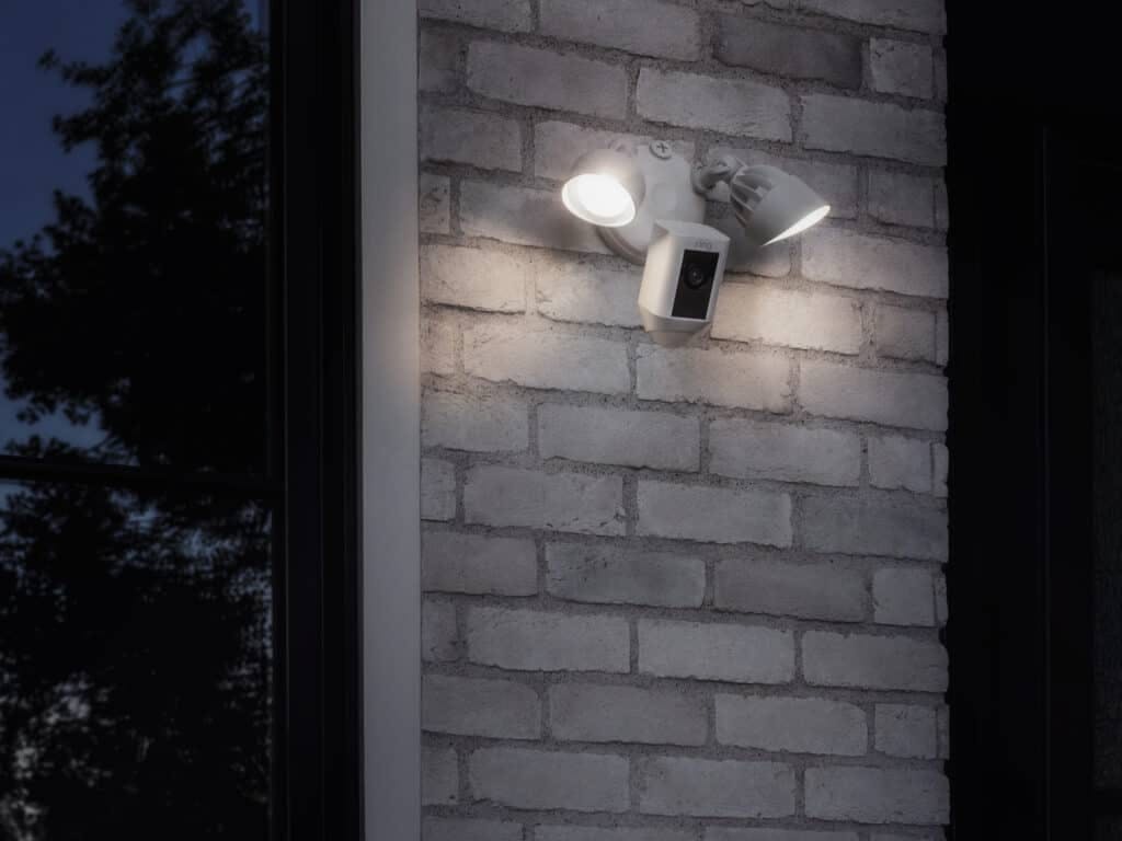 Ring floodlight cam with lights on installed outside home.