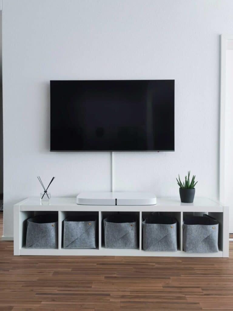 a TV mounted on white wall with shelf
