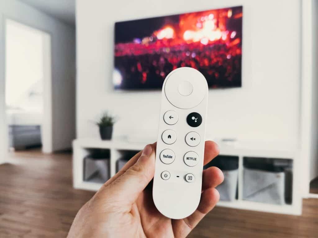 person holding smart remote with tv in background