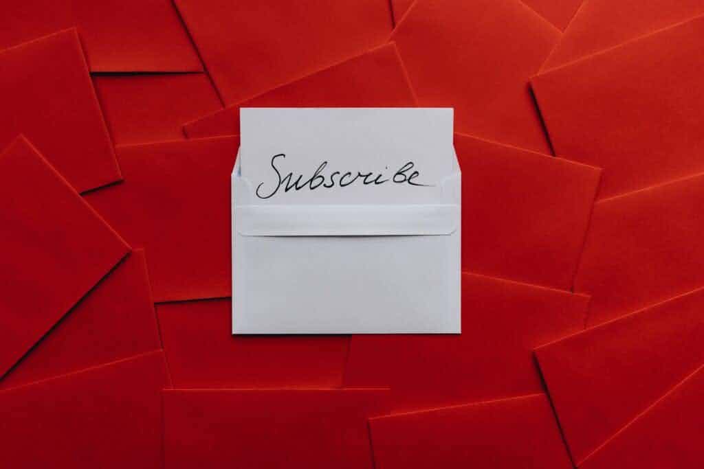white envelope that says Subscribe on it with red envelopes in the background