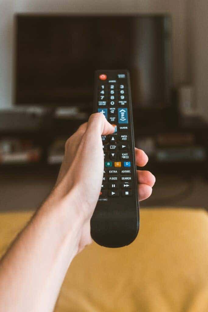 Man pressing a button on a tv remote