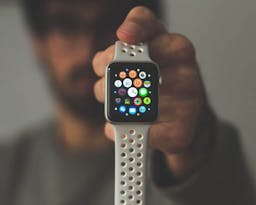 Man with glasses holding up apple watch