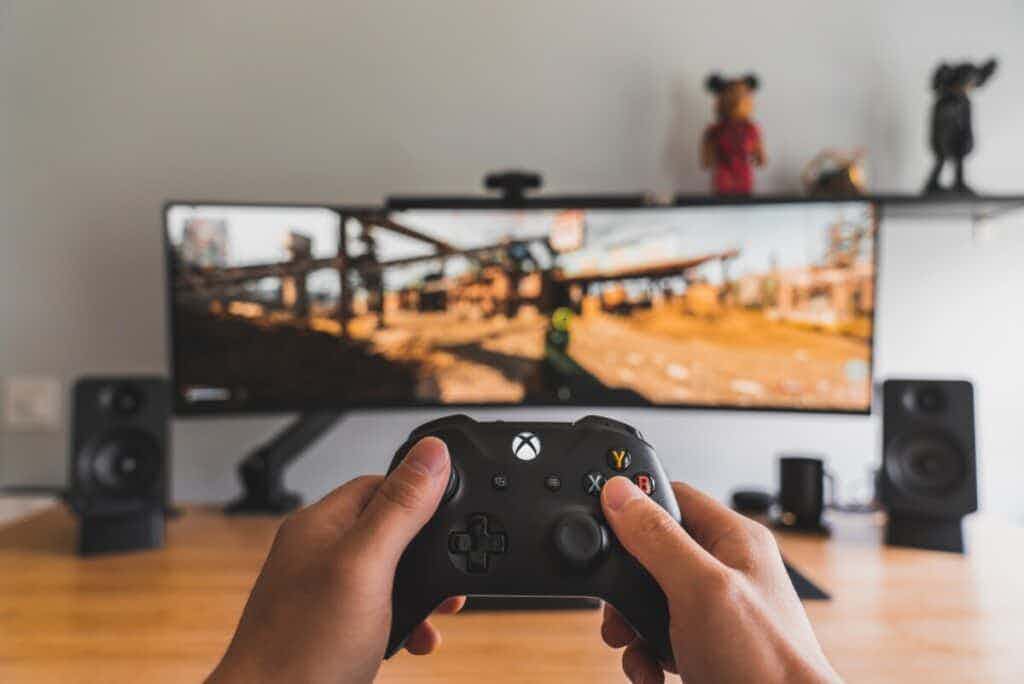 Person playing games with xbox remote on computer monitor