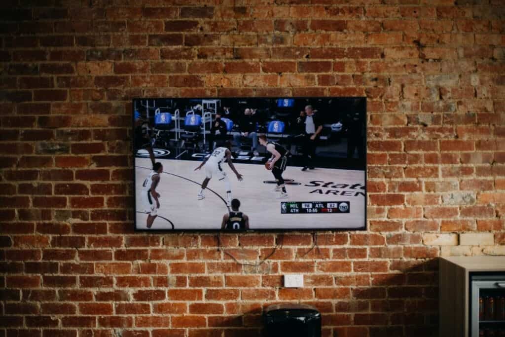 TV with basketball on it hung on brick walls
