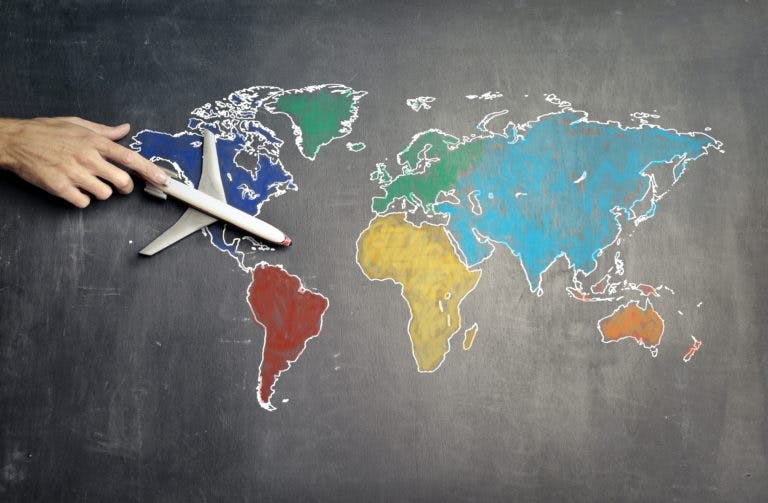 hand holding model plane over world map