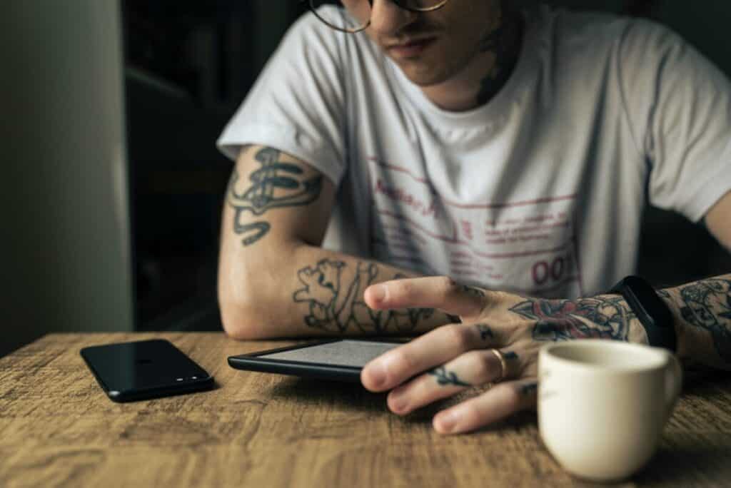 guy with tattoos looking at kindle