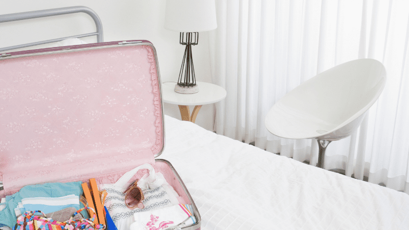 pink suitcase on hotel bed