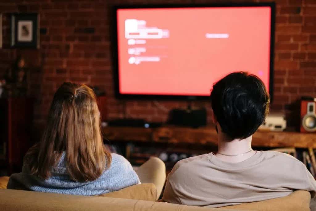 People on couch looking at a TV with a red screen