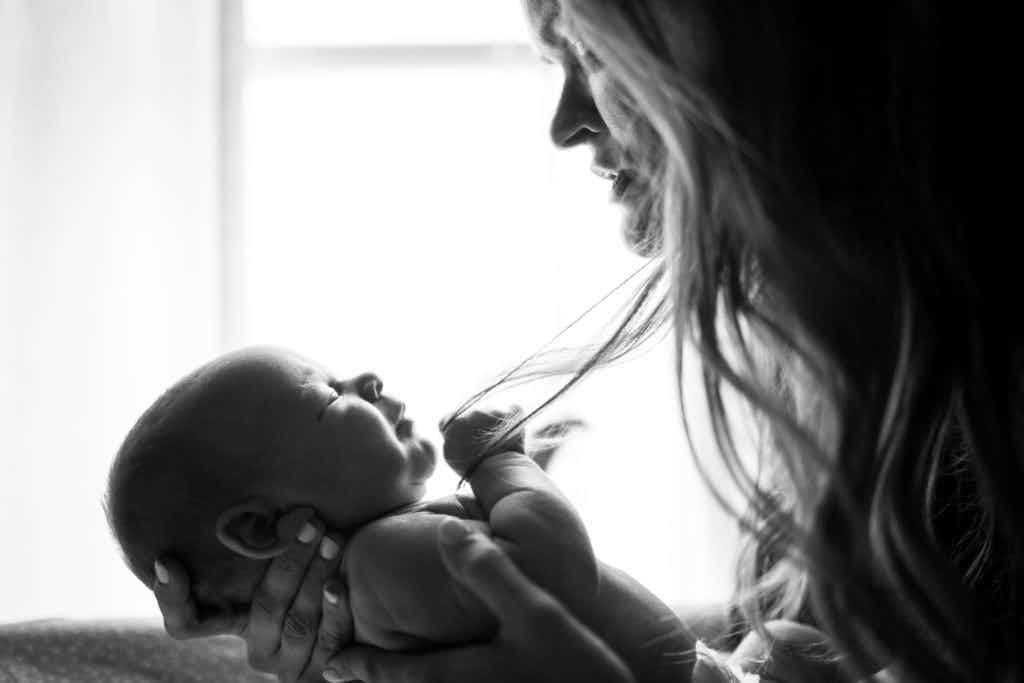 A woman calming and holding her baby.