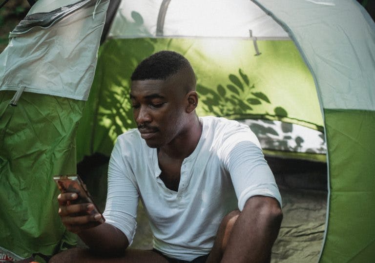 Looking annoyed at a phone in front of a tent