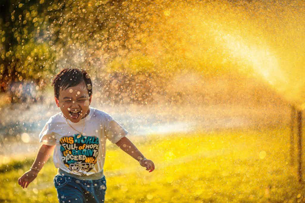 Kid playing in the sprinklers