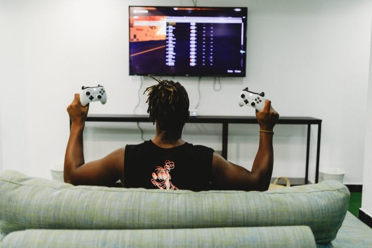 Holding up two Xbox controllers to a screen