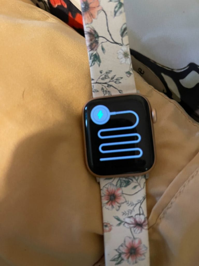 An Apple Watch with a floral band displaying the green snake