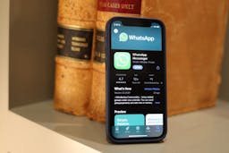 An iPhone on a bookshelf with WhatsApp open